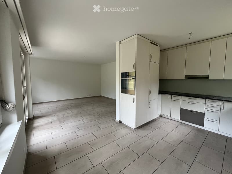 Empty kitchen with white cabinets, tiled floor, and built-in appliances including an oven and dishwasher.
