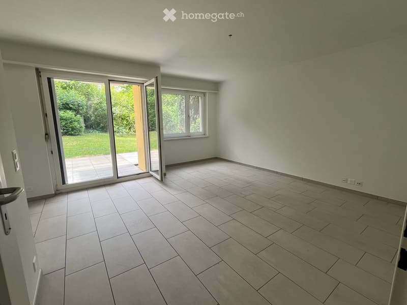 Empty room with tiled floor, light-colored walls, large sliding glass door leading to a patio, and a window on the opposite wall.