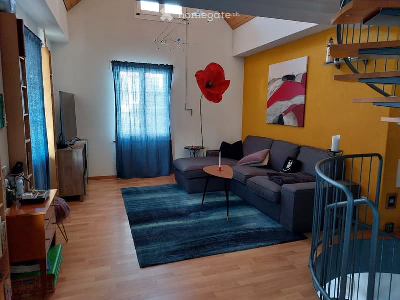 Living room with wooden floor, grey sectional sofa, coffee table, side table, floor lamp, and artwork on the wall.