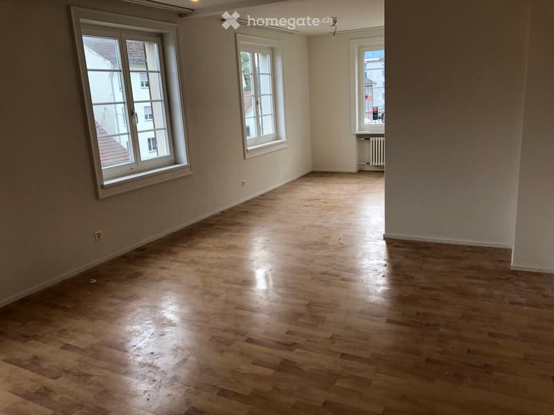 Empty room with wooden flooring, large windows, and neutral-colored walls.