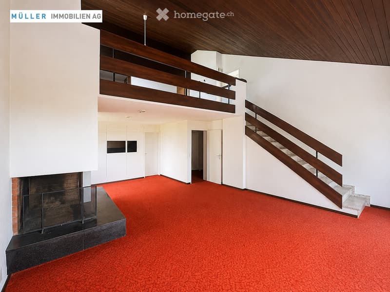 Open hallway with red carpeting, white walls, wooden staircase, and fireplace.