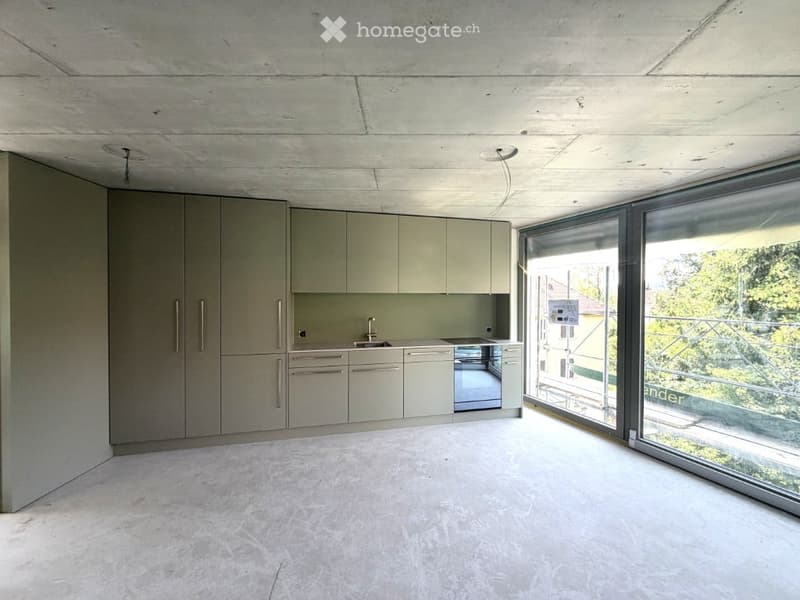 Modern, minimalist kitchen with light grey cabinets, a sink, and expansive windows offering a view of greenery outside.