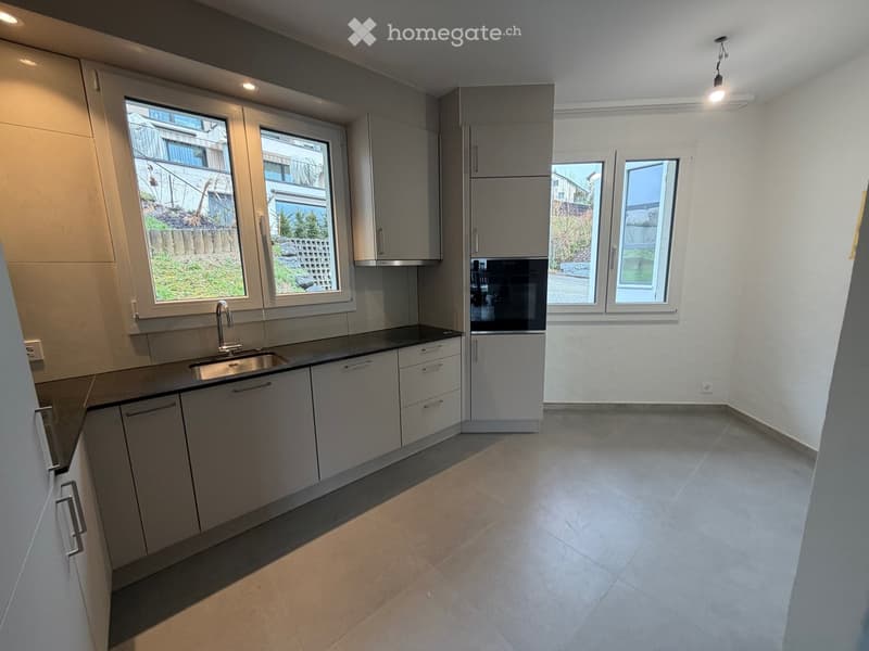 white modern kitchen with large windows, gray floor, stainless steel sink and faucet, kitchen appliances