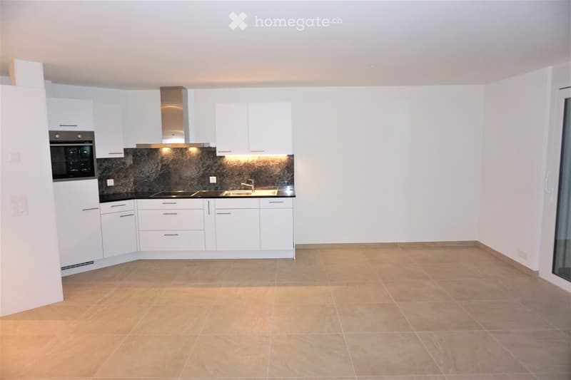 Modern kitchen with white cabinets, stainless steel appliances, and a dark backsplash. Features an oven, range hood, sink, and faucet.