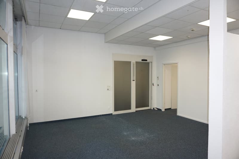 Empty room with white walls, grey carpet, and a glass door leading outside. No furniture or equipment present.