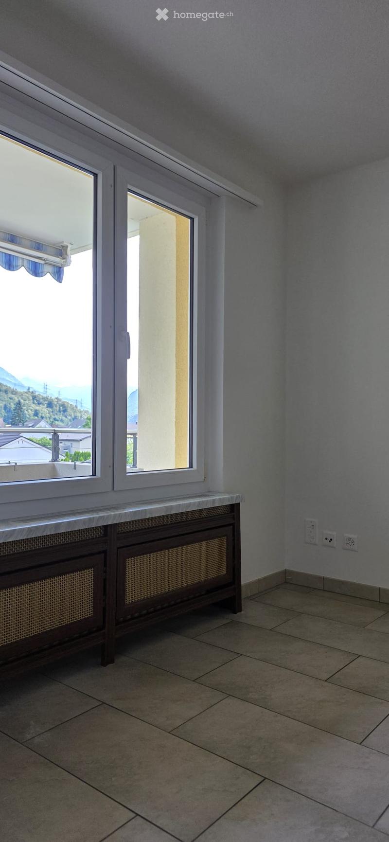 Empty room with tiled floor, radiator, and large windows offering a scenic view.