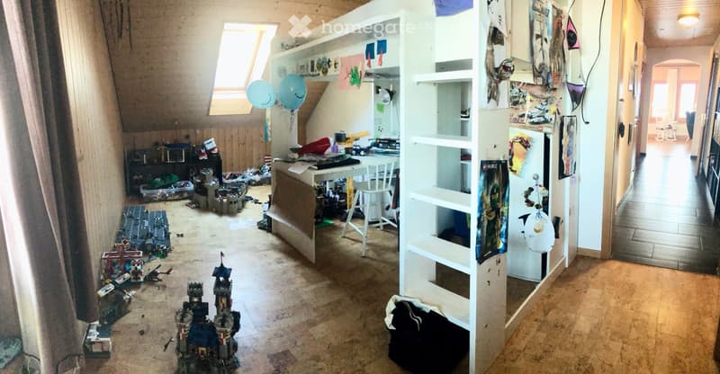 room with wooden floors, bunk bed, toys scattered on the floor, desk with toys, attic windows