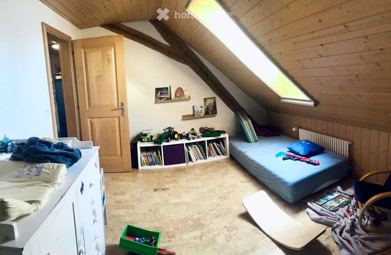 wooden ceiling, wooden floor, blue bed, white wardrobe, radiator, shelves with books, toys, slanted ceiling