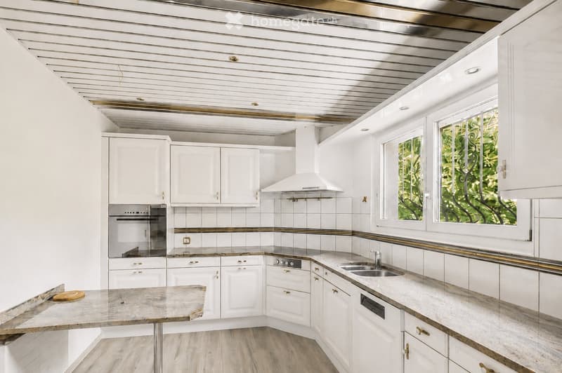 Modern kitchen with white cabinets, stainless steel appliances, marble countertops, and a central island.