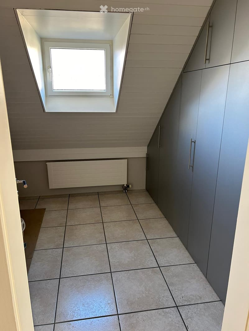 Empty room with tiled floor, grey cabinets, radiator, and a skylight window.