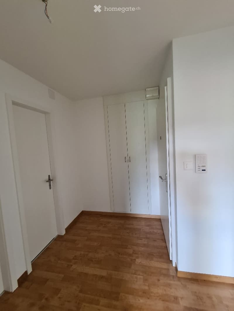 Empty room with light wooden flooring, white walls, and built-in white closet units. No furniture or personal items are present.