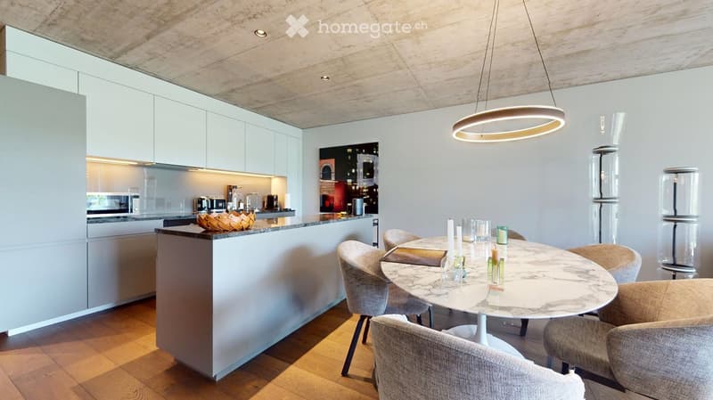 Modern open-plan kitchen and dining area with white cabinets, a central island, a round marble dining table with six chairs, and a pendant light fixture.