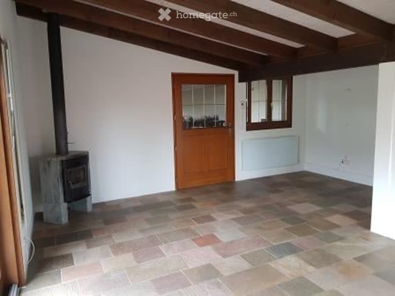 Empty room with fireplace, wooden door, tiled floor, wooden beam