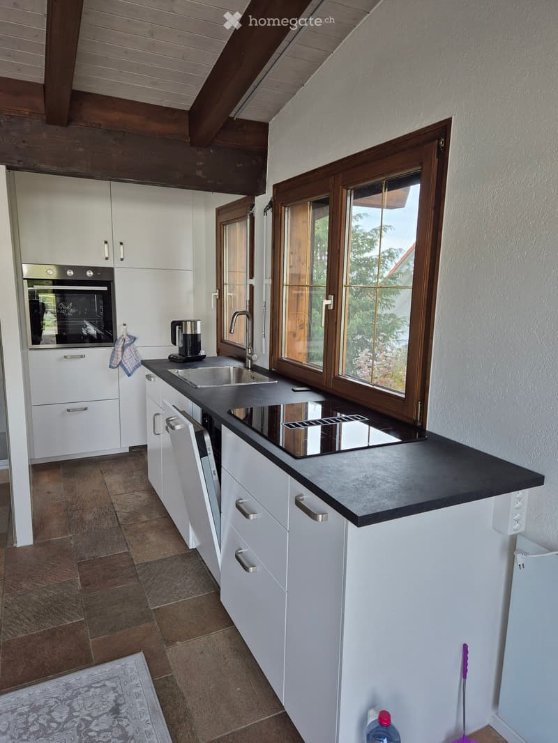 Modern kitchen with white cabinets, black granite countertop, integrated oven and dishwasher, gas stove, sink with a faucet, tiled floor