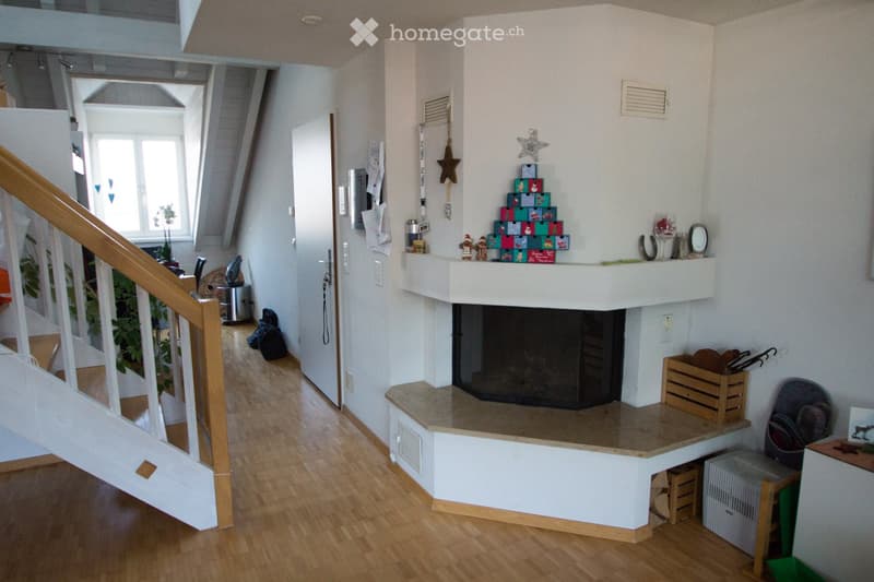 Hallway with wooden flooring, staircase, fireplace, and various decorations including a small Christmas tree and ornaments.