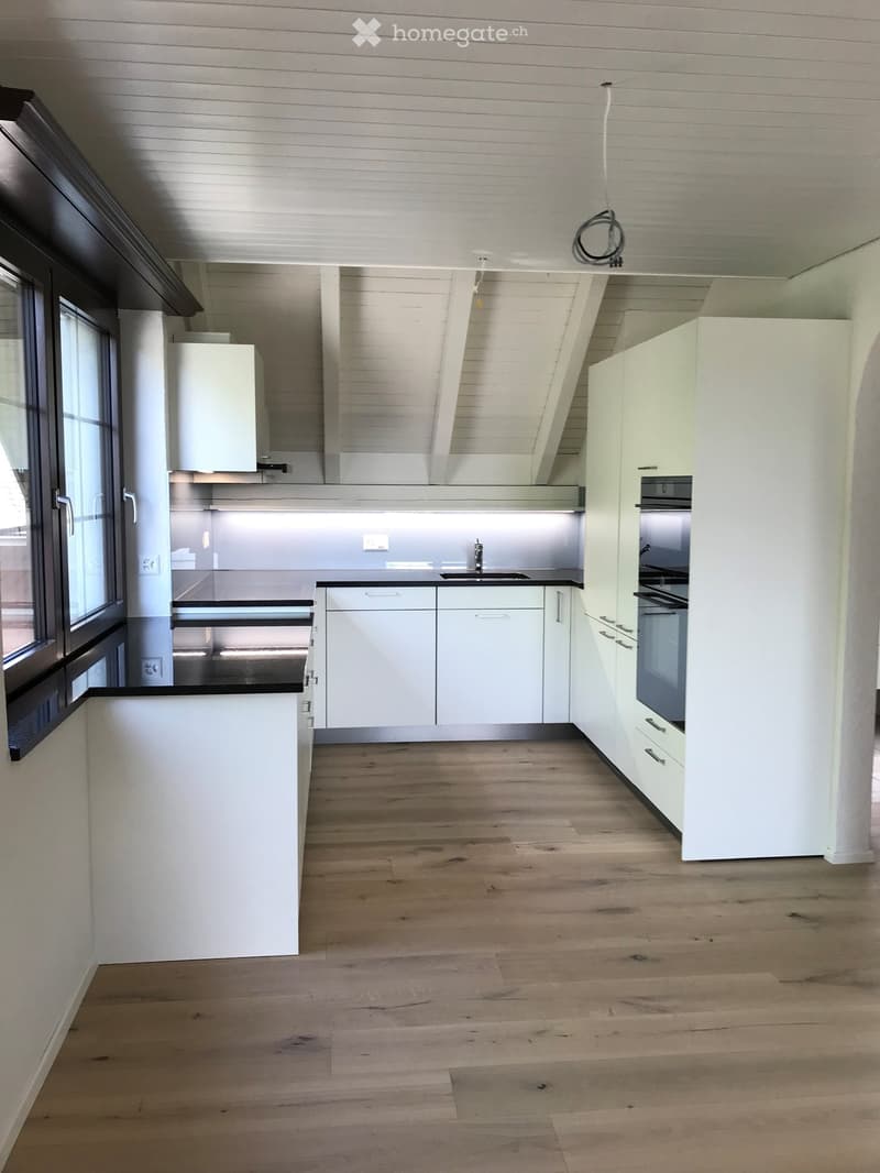 Modern kitchen with white cabinets, wooden flooring, and stainless steel appliances including a sink and oven.