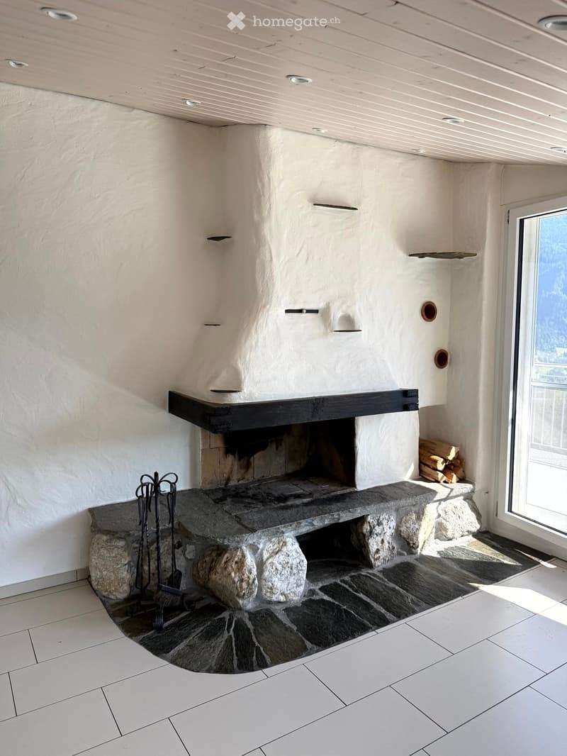 Modern fireplace with stone surround and black mantel, surrounded by tiled flooring and white walls.