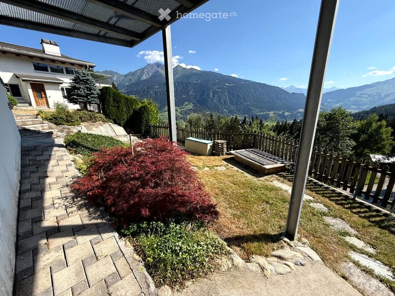 Garden area with a stone pathway, small wooden deck, and a view of mountains in the background.