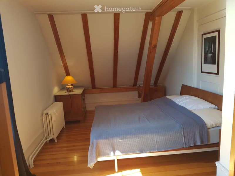 Wooden bed, wooden side tables, lamps, radiator, picture frame, exposed wooden beams