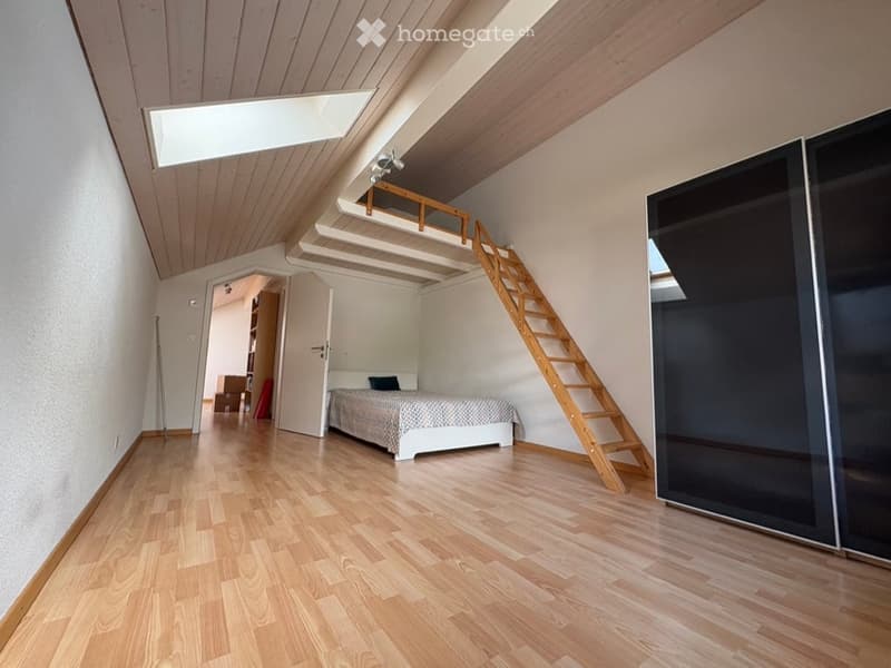 Bedroom. Bright bedroom with wooden flooring, slanted wooden ceiling, skylight, bed, wardrobe, and a wooden staircase leading to a loft area.