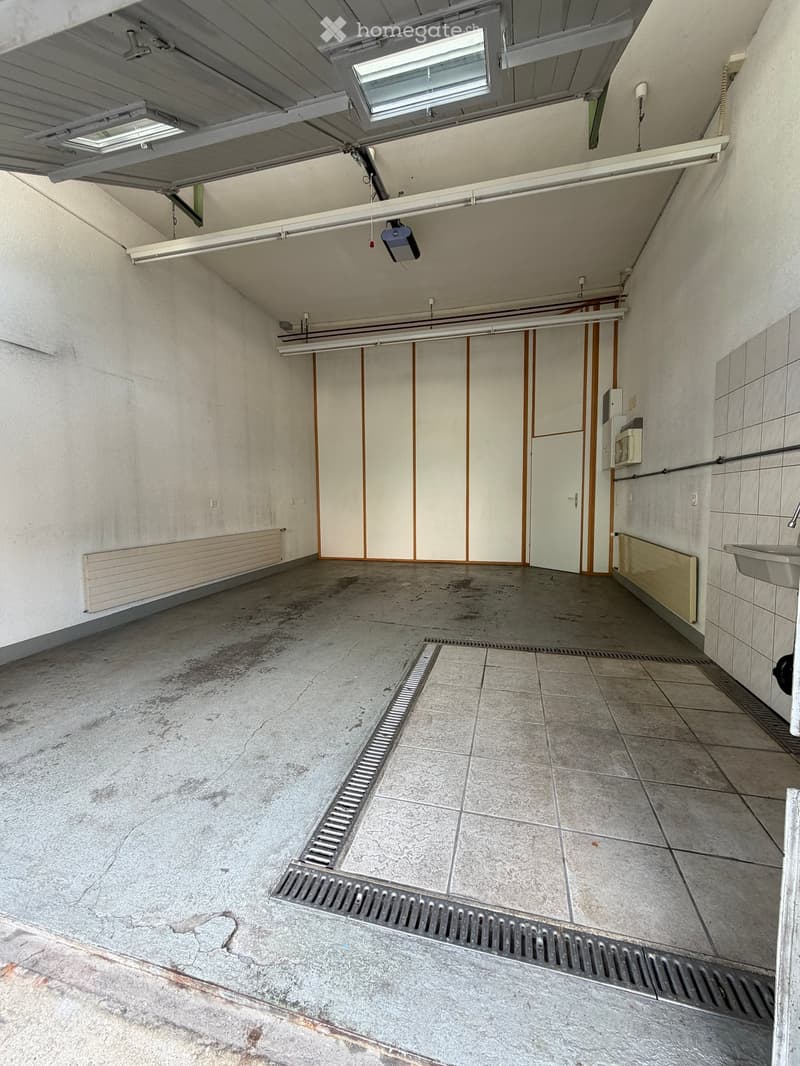 Empty room with concrete floor, tiled section, sink, radiator, and a closed door leading to another space.