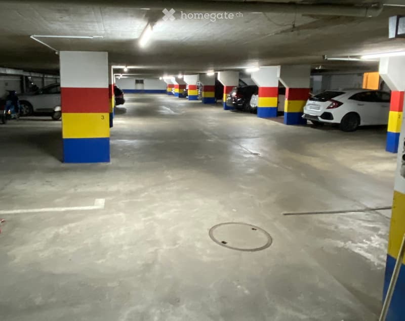 Underground parking area with several parked cars, concrete pillars, and numbered sections.
