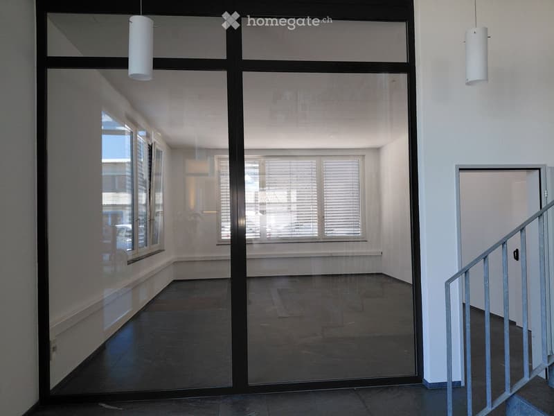 Empty hallway with glass doors, white walls, and a staircase on the right side.