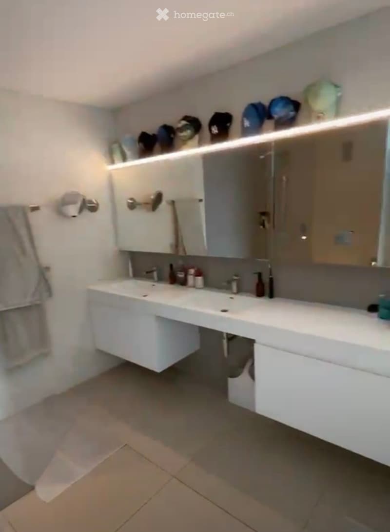 Modern bathroom with a white double sink vanity, mirrored cabinet, and tiled floor.