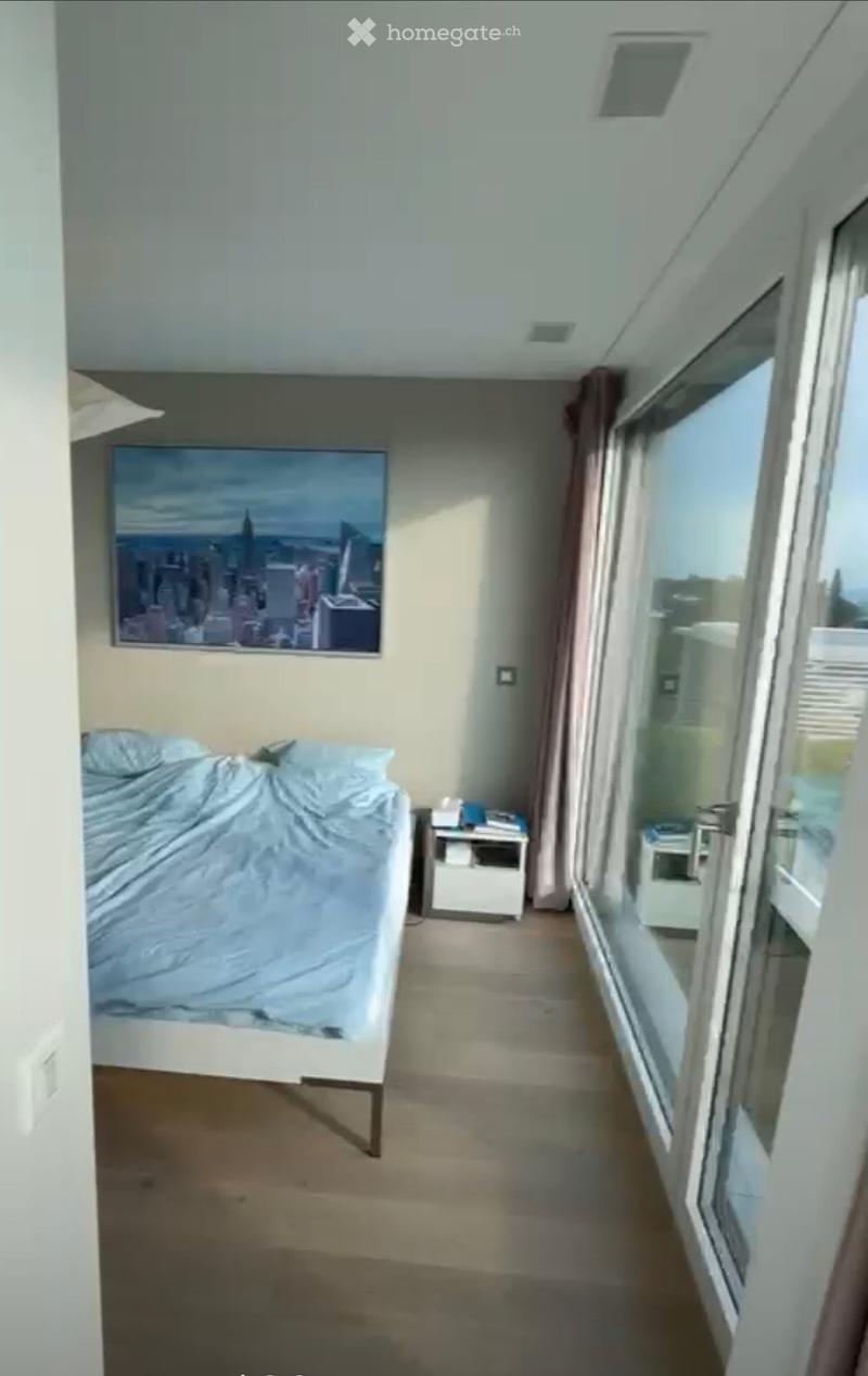 Modern bedroom with a single bed, nightstand, and large window with cityscape view.