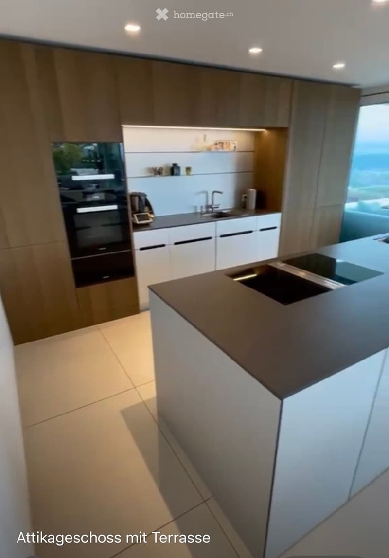 Modern kitchen with white and brown cabinets, a central island with a dark countertop, and built-in appliances including an oven and sink.