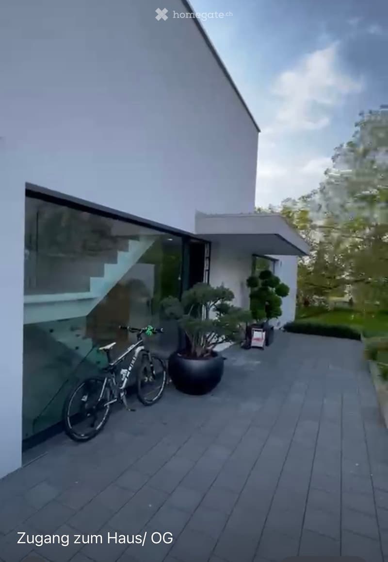 Modern outdoor area with a paved patio, bicycle, and potted plants near a contemporary house.