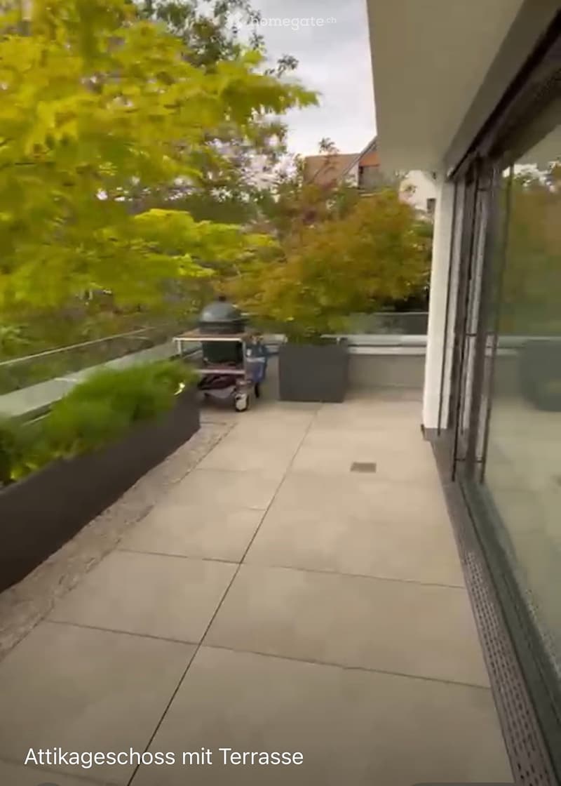 Balcony with tiled floor, glass railing, and outdoor furniture including a grill and table.
