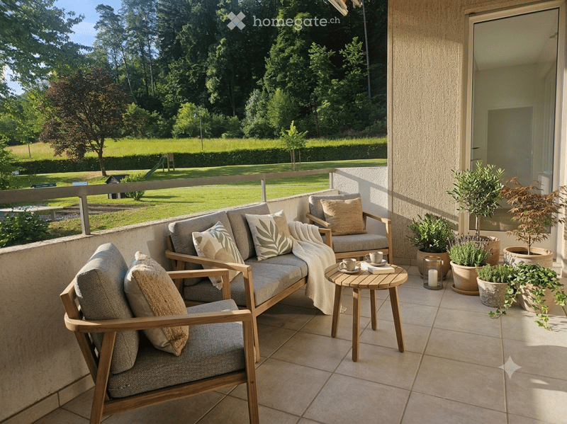 Balcony with wooden furniture, sofa, chairs, small table, and potted plants, overlooking a green park.