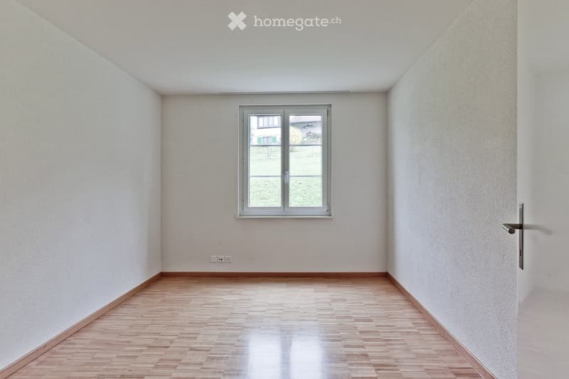 white walls, wooden floor, a window with view of a landscape, power outlets