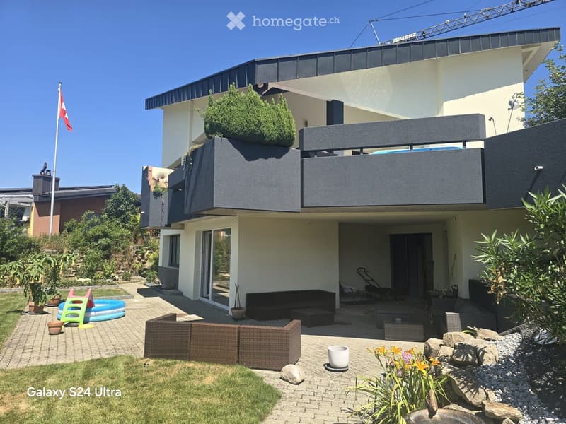 Modern garden area with a patio, outdoor seating, a small inflatable pool, and decorative elements like rocks and flower pots.