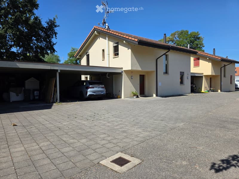 Two-story house with beige exterior, red-tiled roof, garage, and driveway.
