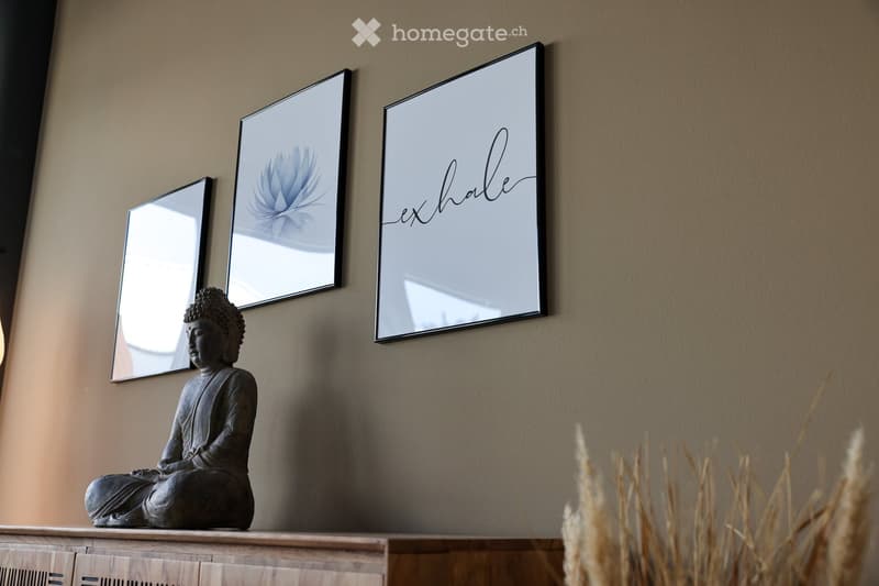 A wooden cabinet with a Buddha statue and three framed pictures, including a mirror and a decorative design.