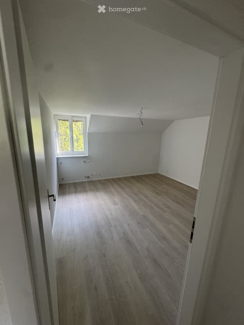Empty room with wooden flooring, white walls, and a window letting in natural light. No furniture or equipment present.