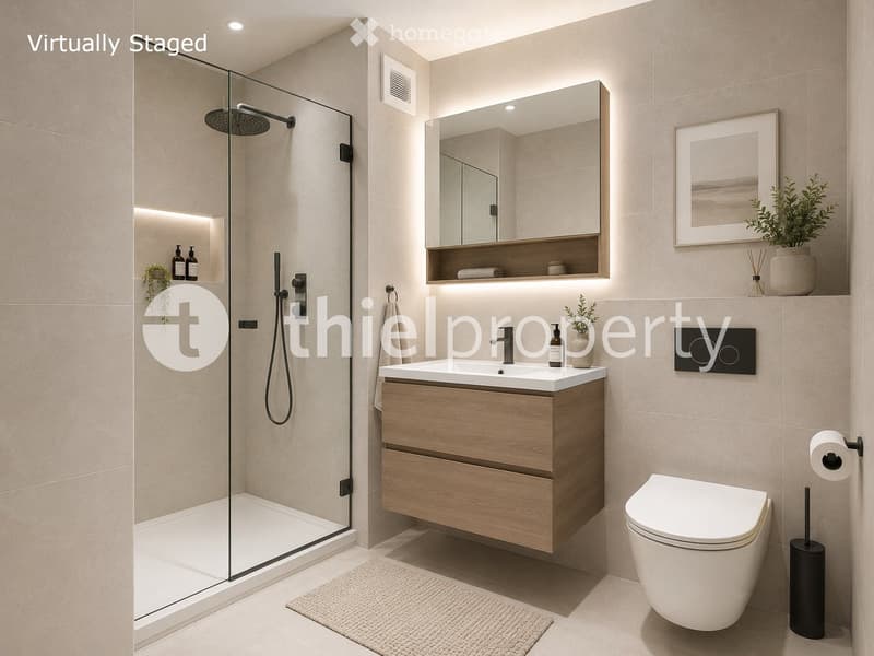 Modern bathroom with a glass-enclosed shower, a wooden vanity with a sink, a toilet, a mirror, and decorative plants.