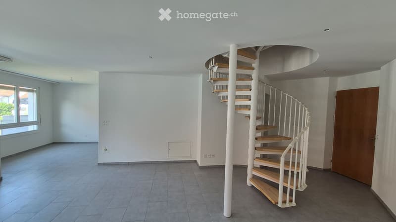 Empty hallway with tiled floor, white walls, and two spiral staircases leading upwards.