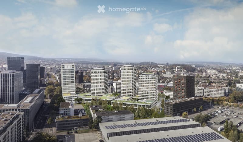 Aerial view of a modern urban area with multiple high-rise buildings, green spaces, and parking lots.