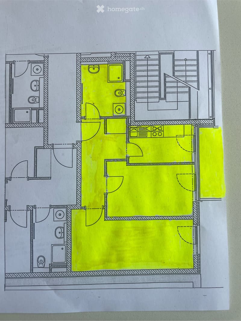 Floor plan of a residential space with multiple rooms including a large central living area, smaller rooms, and a staircase leading to an upper level.