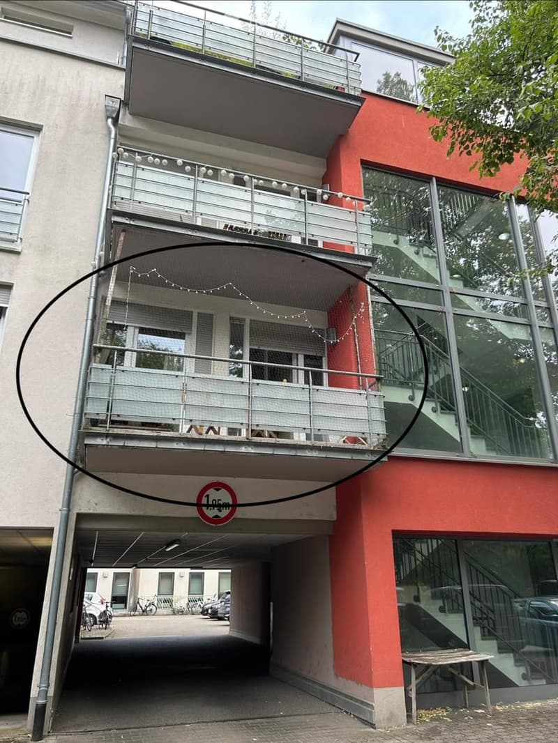 Multi-story building with balconies, garage entrance, and modern glass facade.