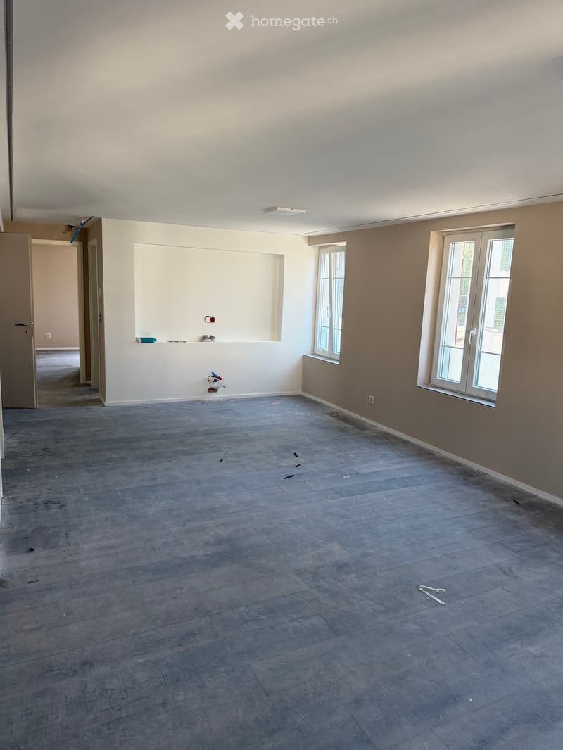 Empty room with wooden flooring, white walls, and large windows. No furniture or equipment present.