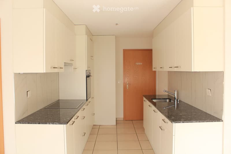 Modern kitchen with white cabinets, granite countertops, a sink with a modern faucet, and an oven. The space is clean and well-lit with tiled flooring.