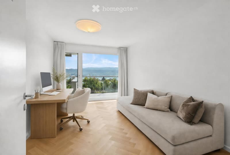 Bright, modern living space with a sofa, desk, and large windows offering a scenic view.