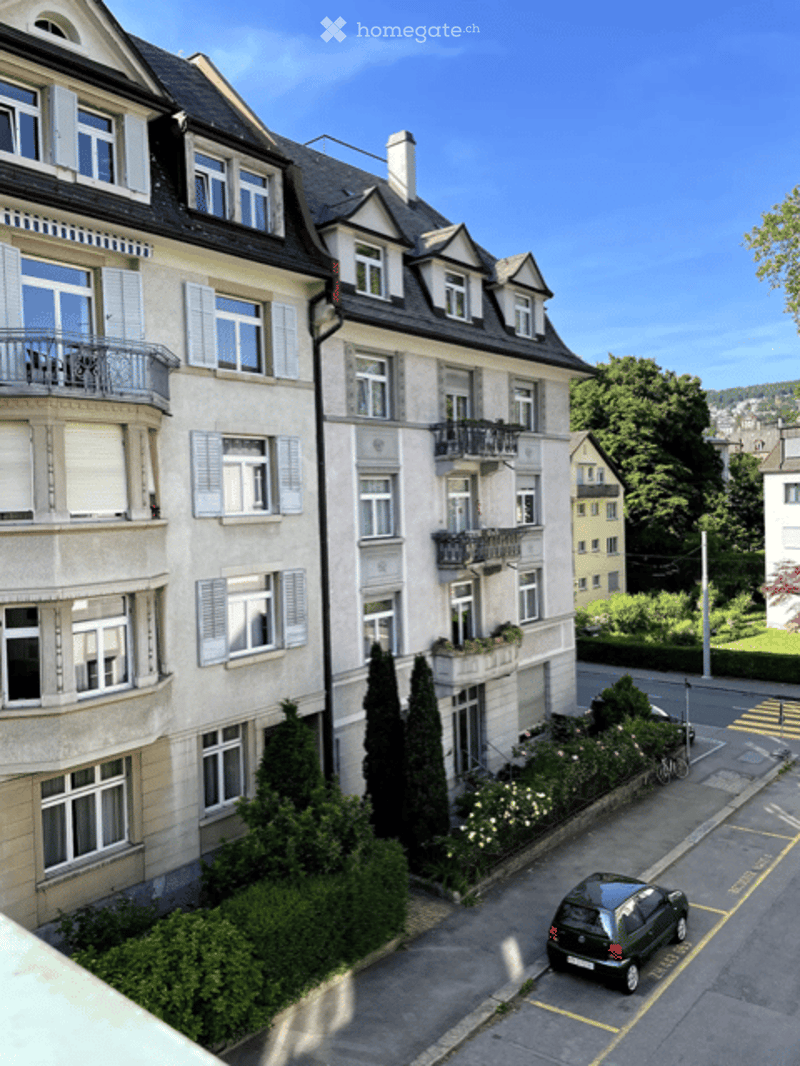 Multi-story residential building with multiple balconies, large windows, and classic architectural details.