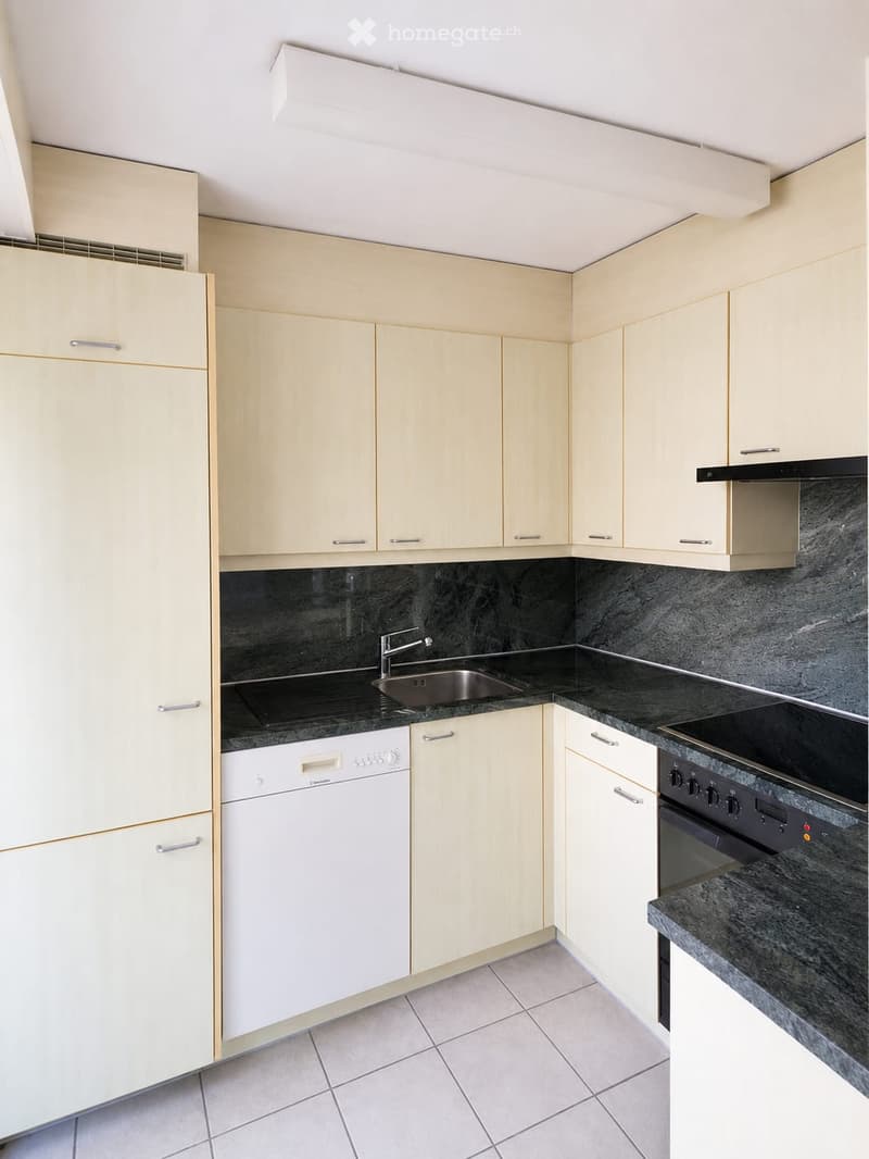 Modern kitchen with light-colored cabinets, granite countertops, a stainless steel sink, and built-in appliances including a dishwasher and oven.