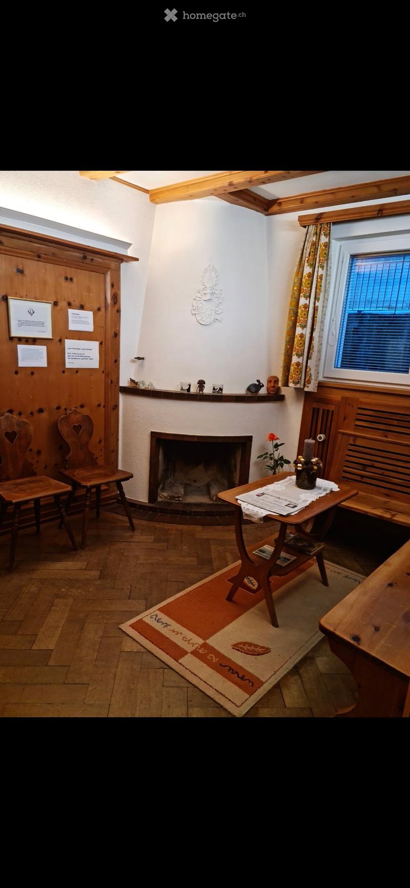 Cozy living room with wooden furniture, fireplace, small table, chairs, and decorative items on a shelf.