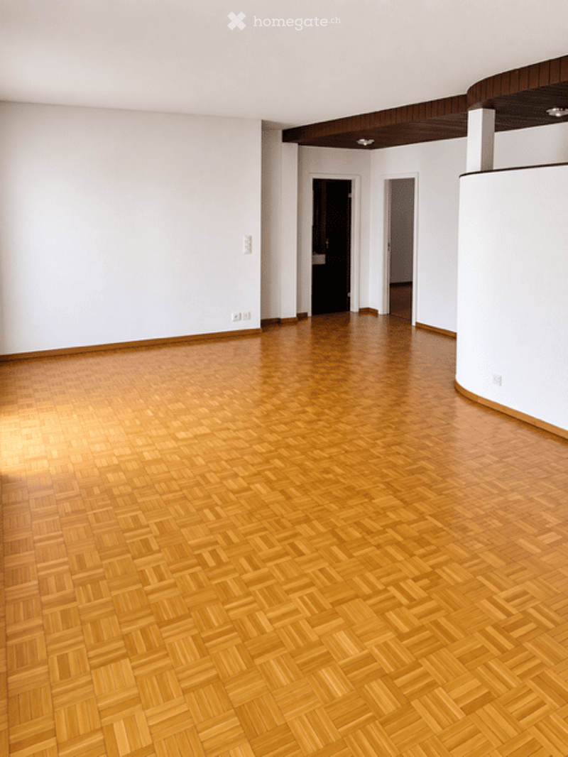 Completely empty room with wooden herringbone flooring, white walls, and recessed lighting. No furniture or equipment present.